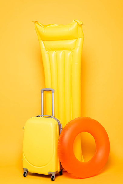 travel bag with pool floats on yellow background - Zdjęcie, obraz