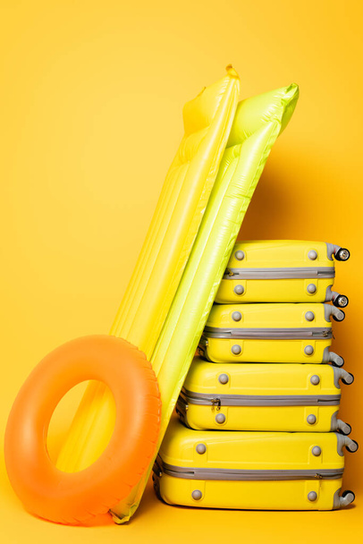 travel bags with pool floats on yellow background - Photo, Image