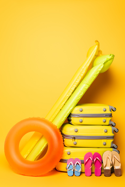 sacs de voyage avec tongs familiales et flotteurs de piscine sur jaune - Photo, image
