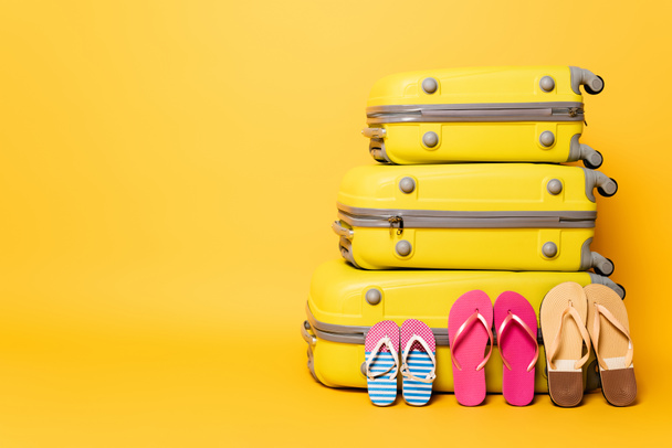 sacs de voyage avec des tongs familiales isolées sur jaune - Photo, image