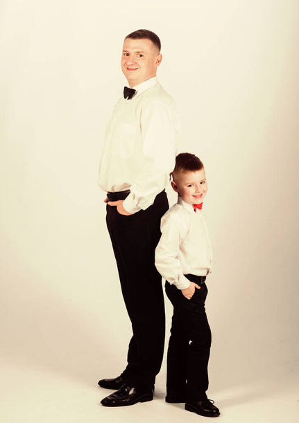 Dad and boy white shirts with bow ties. Gentleman upbringing. Little son following fathers example of noble man. Gentleman upbringing. Father and son formal clothes outfit. Grow up gentleman - Photo, image