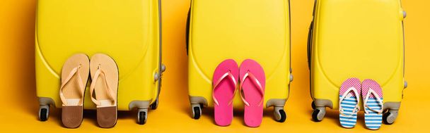 torby podróżnicze z rodzinnymi japonkami odizolowane na żółtym, panoramicznym ujęciu - Zdjęcie, obraz