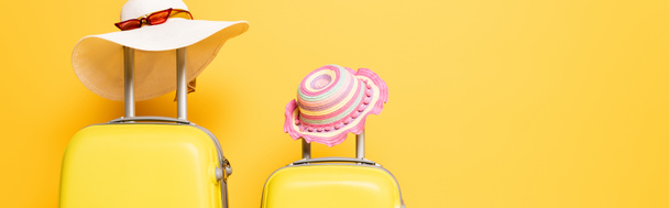 mother and daughter travel bags with sun hats and sunglasses isolated on yellow, panoramic shot - Photo, Image