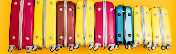 барвисті туристичні сумки в стосі ізольовані на жовтому, панорамний постріл
 - Фото, зображення