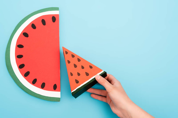 partial view of female hand with paper watermelon slices on blue background - Photo, Image