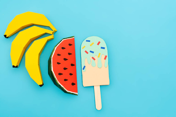 top view of paper watermelon, bananas and ice cream with sprinkles on blue background - Foto, Imagen