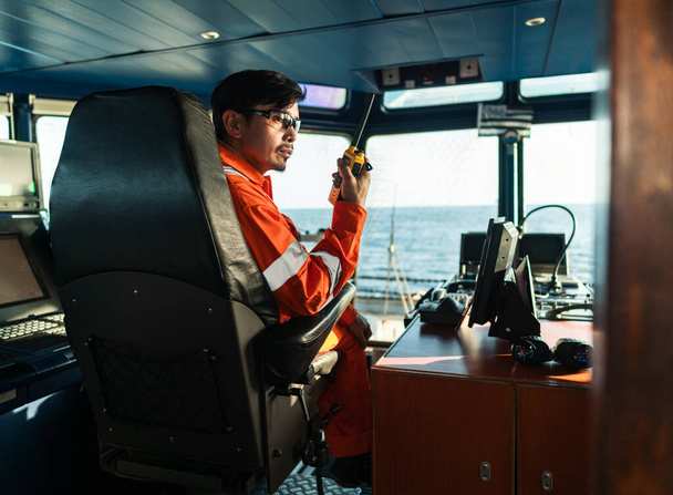 Fülöp-szigeteki tiszt a hajó vagy hajó hídján. A GMDSS VHF rádión beszél. - Fotó, kép