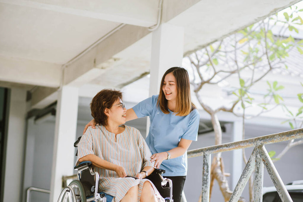 Улыбающийся физиотерапевт заботится о счастливом пожилом пациенте в инвалидном кресле - Фото, изображение