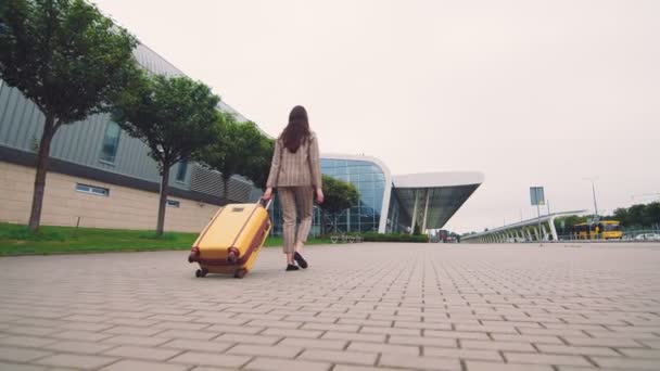 Woman walking with luggage. The girl goes on a journey and walks to the airport. A businesswoman walks down the street with luggage in her hand and explores the city. - Metraje, vídeo