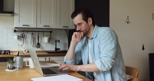 Pensive businessman work on laptop feels doubtful, search issue solution - Кадри, відео