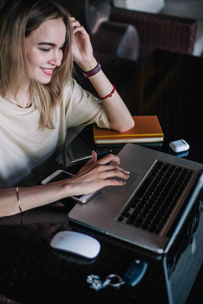 Young slender girl at the restaurant table works behind a laptop - Photo, Image