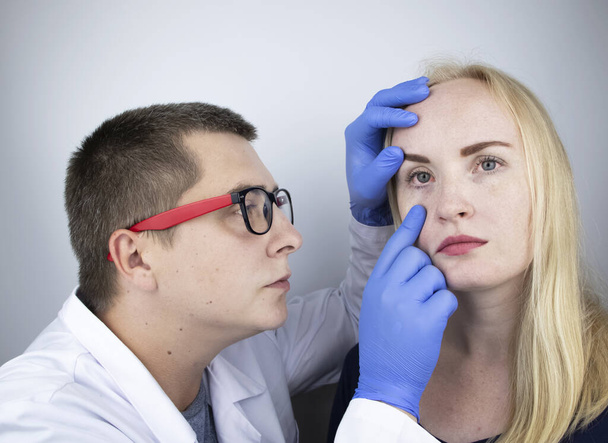Un oftalmologo esamina una donna che si lamenta di una sensazione di bruciore e dolore agli occhi. Affaticamento degli occhi da uno schermo del computer o telefono (sensazione di sabbia sulla cornea). Il concetto di diagnosi precoce del glaucoma - Foto, immagini