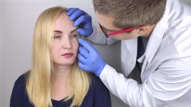 Un oftalmólogo examina a una mujer que se queja de una sensación de ardor y dolor en los ojos. Fatiga ocular desde una pantalla de ordenador o teléfono (sensación de arena en la córnea). El concepto de diag temprano
 - Metraje, vídeo