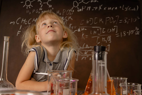Curious little girl with test tubes and colorful substances makes tests at school laboratory. Small kid learning chemistry and conducts science experiment on biology lesson. Biology education concept. - Photo, Image