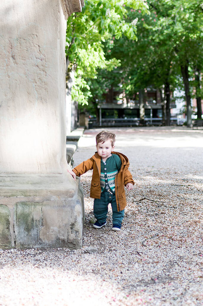 Un bebé de un año y medio de edad dando sus primeros pasos en un parque con un piso de piedra suelta, está aprendiendo a caminar
 - Foto, Imagen
