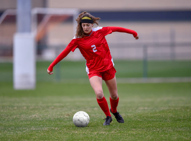 Genç çekici atletik kız bir oyunda futbol oynuyor. - Fotoğraf, Görsel
