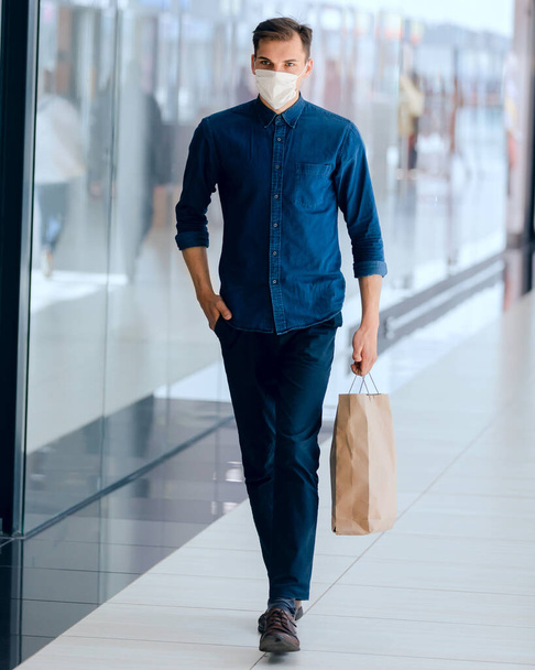 man in a protective mask passing near a supermarket. - Photo, image