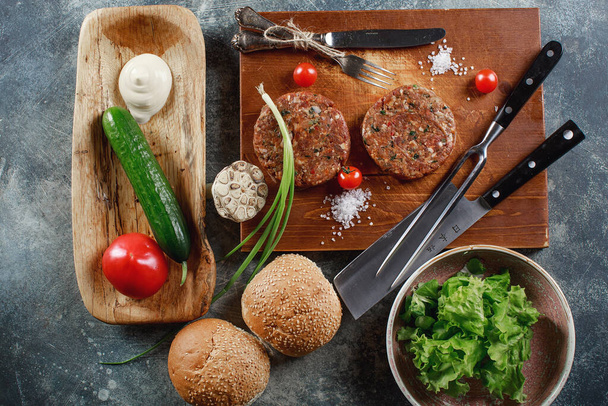 Raw Ground beef meat Burger steak cutlets with ingredients on the board. - Photo, Image
