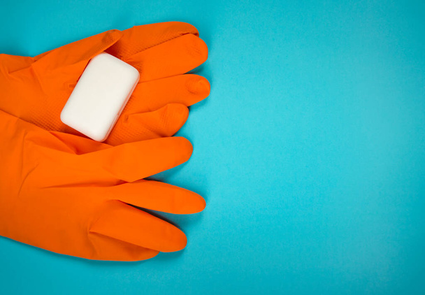 Wash your hands. Protective gloves with soap bar on blue background flat lay. Infection prevention. - Photo, Image