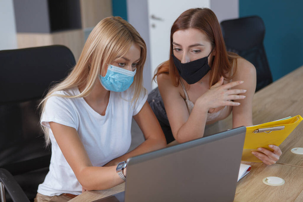 Female colleagues wearing protective face masks at the office - Foto, Imagen