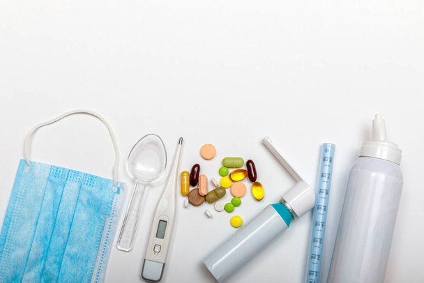 Treatment of colds and flu. Various medicines, a thermometer, sprays from a stuffy nose and a pain in a throat on a white background. High resulotion image. Medicine flat lay concept. - Photo, Image
