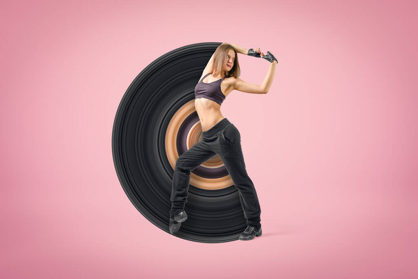 Young sporty woman dancer wearing black outfit on pink background - Foto, Bild