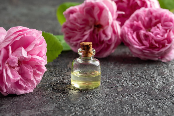 A bottle of essential oil with fresh rose de mai flowers - Foto, Imagen