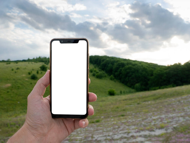 Hand holding smart phone with blurred backgroung. Blank screen for montage. Mockup image. - Fotografie, Obrázek