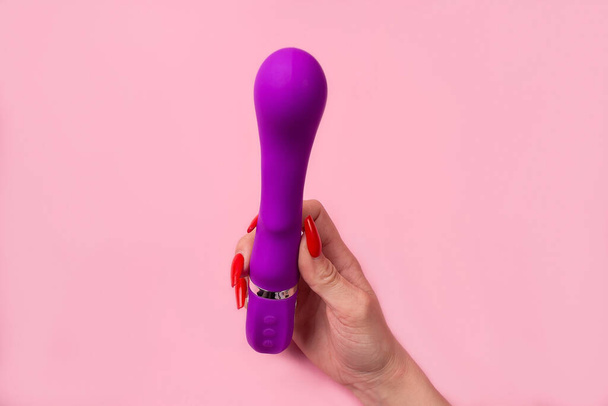 the Dildo in hand on a pink background, sex toy - Fotó, kép