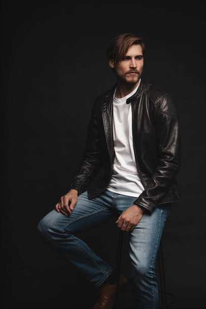 Fashion man, Handsome serious beauty male model portrait wear leather jacket, young guy over black background. - Foto, Imagem