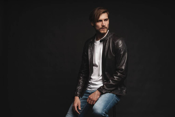 Fashion man, Handsome serious beauty male model portrait wear leather jacket, young guy over black background. - Foto, Imagen