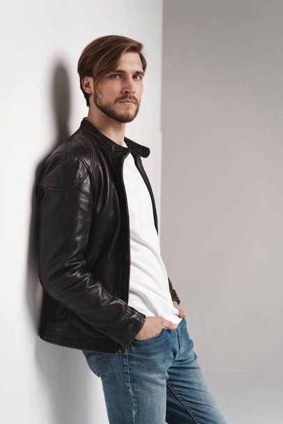 Fashion man, Handsome serious beauty male model portrait wear leather jacket, young guy over white background. - Foto, imagen
