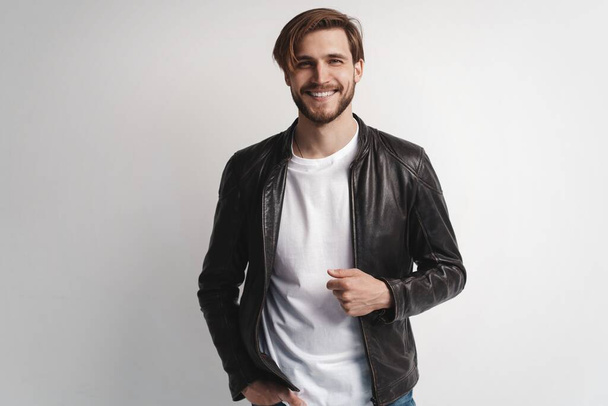 Fashion man, Handsome serious beauty male model portrait wear leather jacket, young guy over white background. - Foto, Imagen