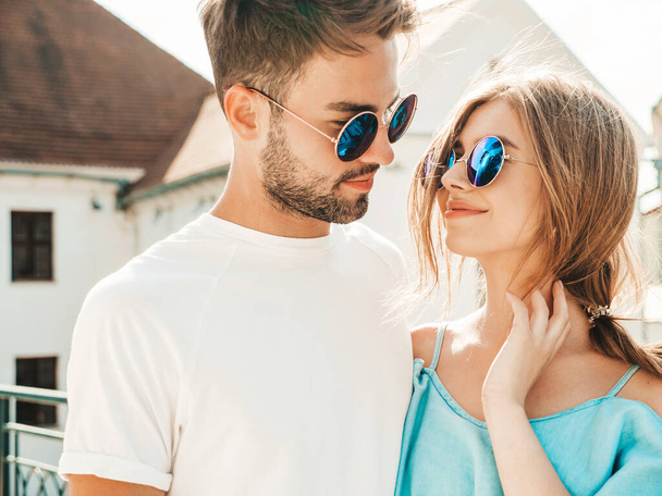 Portrait of smiling beautiful woman and her handsome boyfriend. Woman in casual summer jeans dress. Happy cheerful family. Female having fun. Couple posing on the street background in sunglasses - Zdjęcie, obraz