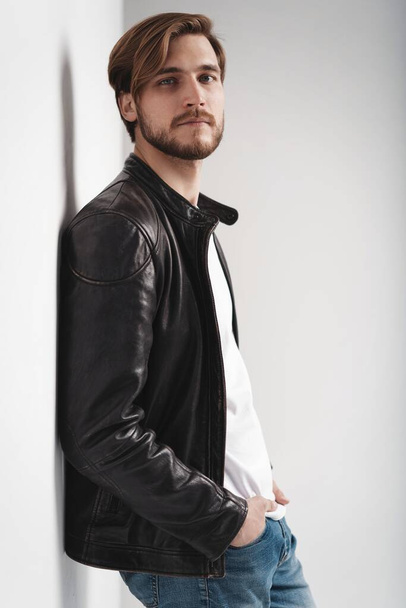 Fashion man, Handsome serious beauty male model portrait wear leather jacket, young guy over white background. - Photo, Image