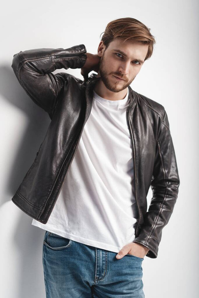 Fashion man, Handsome serious beauty male model portrait wear leather jacket, young guy over white background. - Foto, afbeelding