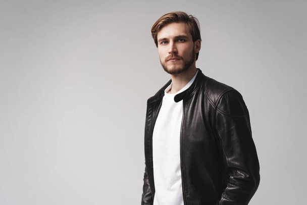 Fashion man, Handsome serious beauty male model portrait wear leather jacket, young guy over white background. - Fotó, kép