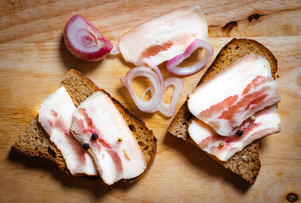 Lard with black bread and onions on a wooden board. - Photo, Image