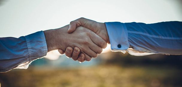 Business handshake and business people concepts. Two men shaking hands on sunset background. High resulotion image. - Foto, Imagem
