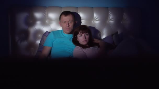 Пара смотрит страшный фильм ночью, мужчина закрывает глаза женщины рукой, движение камеры - Кадры, видео
