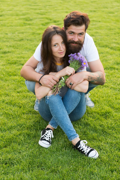Happy womens day. Bearded man give flowers to sexy woman. Happy couple in love on green grass. Celebrating womens day. Floral shop. International womens holiday. Womens day on 8 March - Foto, imagen