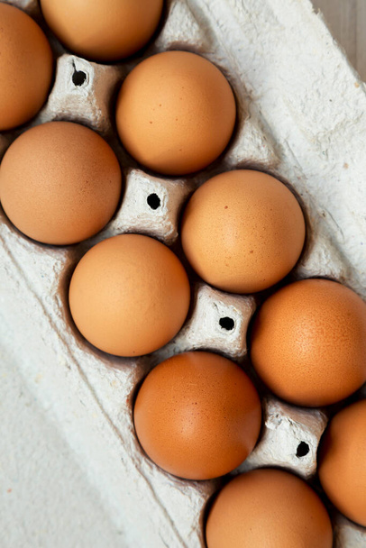 Rohe braune Eier in einer Pappschachtel, Draufsicht. Flach liegend, über Kopf, von oben. Nahaufnahme. - Foto, Bild