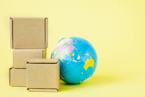 Earth globe is surrounded by boxes. Global business and international transportation of goods products. Shipping freight, world trade and economics. Distribution, import export. Commodity turnover. - Photo, image