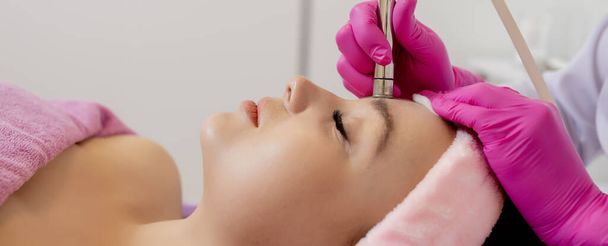 The cosmetologist makes the procedure Microdermabrasion of the facial skin of a beautiful, young woman in a beauty salon.Cosmetology and professional skin care - Foto, Imagen