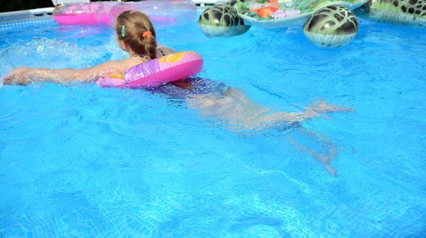 Παιδί και διασκεδάζει στην πισίνα. Παιδί κορίτσι μέσα σε μια μπλε πισίνα το καλοκαίρι. - Φωτογραφία, εικόνα