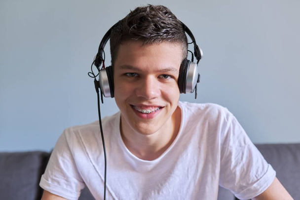 Portrait of student boy teenager in headphones looking at webcam, videocall - 写真・画像