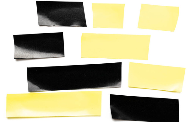 Lepicí lepicí papír. Kousek žluté a černé lepicí pásky izolované na bílém pozadí. Roztrhané pruhy grunge textury - Fotografie, Obrázek