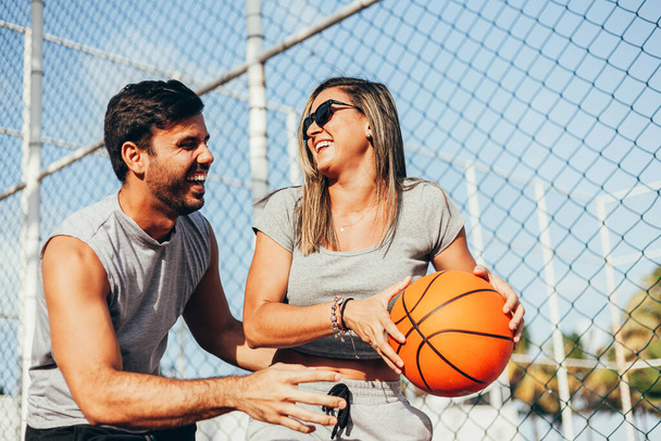 Couple having fun playing basketball outdoors on sunny day. - Фото, зображення