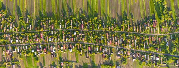 伝統的な村、ウクライナの鳥の目のビュー。緑の木々の間に多くの小屋、よく手入れされた農地の近くに、未舗装の道路は、村に沿ってストレッチ。上空からの風光明媚な田園風景の空中ドローンビュー - 写真・画像
