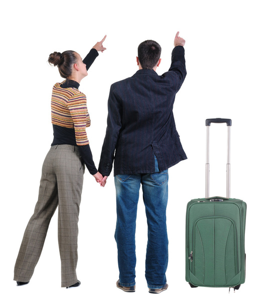 Young couple traveling with suitcase and pointing at wall - Foto, Bild